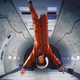A young boy in an orange jumpsuit and white helmet happily spins upside down in a zero-gravity chamber